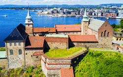 Burganlage am Wasser mit Stadt im Hintergrund bei sonnigem Wetter