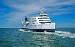 Eine große weiße Fähre fährt über ein ruhiges Meer mit blauem Himmel im Hintergrund.