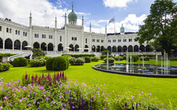 Gebäude mit Kuppeln und Türmen in einem blühenden Garten mit Springbrunnen.
