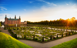 Schloss mit barockem Garten bei Sonnenuntergang.
