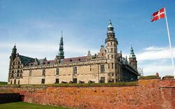 Schloss Kronborg in Dänemark mit dänischer Flagge im Vordergrund.