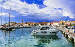Boote im Hafen, historische Stadt im Hintergrund, blauer Himmel mit Wolken.