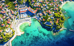 Luftaufnahme einer Küstenstadt mit türkisblauem Wasser und dicht bebauten Häusern.