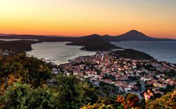 Stadt am Meer bei Sonnenuntergang mit Bergen im Hintergrund