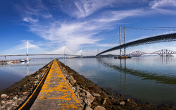 Brücken am Firth of Forth in Schottland mit blauem Himmel und Wasserspiegelungen.
