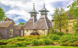 Historische Brennerei mit Pagodendächern und gepflegtem Garten.