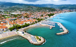 Luftaufnahme einer Küstenstadt mit Strand und Jachthafen.