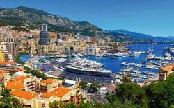 Panoramablick auf einen Yachthafen in einer Küstenstadt, umgeben von Hügeln und dichter Bebauung.