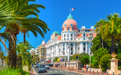 Boulevard in Nizza mit Hotel und Palmen im Vordergrund.