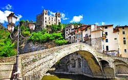 Historische Steinbrücke in mittelalterlicher Stadt mit Burg und blauen Himmel.