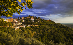 Hügelstadt bei Sonnenuntergang im Grünen mit dramatischem Himmel.