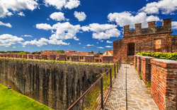 Historische Festungsmauer mit Zinnen und blauem Himmel im Hintergrund.