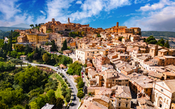 Mittelalterliche Stadt auf einem Hügel mit vielen engen Gassen und bäuerlicher Umgebung.