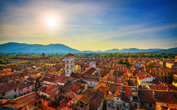 Stadtansicht bei Sonnenuntergang mit Bergen im Hintergrund.