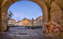 Roter Fahrradrahmen in historischer Stadt mit Arkadenansicht, menschenleerer Platz.