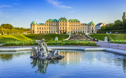 Barockschloss mit Garten und Teich im Vordergrund bei sonnigem Himmel.