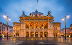 Historische Fassade der Wiener Staatsoper in Österreich bei Dämmerung mit Beleuchtung.