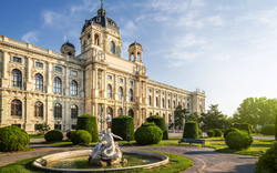 Historisches Gebäude mit Garten und Brunnen im Vordergrund.