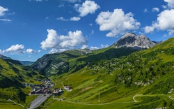 Berglandschaft mit Tal, Siedlung und blauem Himmel mit Wolken.