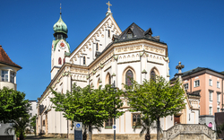 Historische Kirche mit Zwiebelturm bei blauem Himmel.