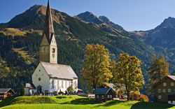 Kirche vor alpiner Berglandschaft bei sonnigem Wetter