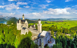 Schloss Neuschwanstein umgeben von Wäldern und Bergen im Sommer.
