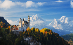 Schloss Neuschwanstein vor Alpenkulisse im Herbst.
