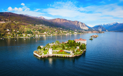 Luftaufnahme einer Insel mit historischem Gebäude in einem See umgeben von Bergen.