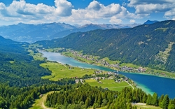 Luftaufnahme einer alpinen Seenlandschaft mit Bergen im Hintergrund