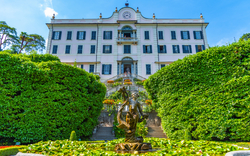 Historisches Gebäude mit Garten und Brunnen im Vordergrund.
