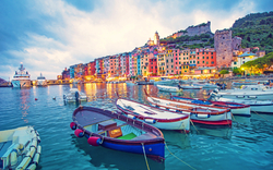 Bunte Häuser und Boote im Hafen von Portovenere, Italien, bei Sonnenuntergang.