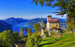 Haus auf einem Hügel mit Blick auf einen See und umliegende Berge.