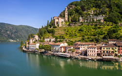 Küstenstadt am See mit Hügel und Kirche im Hintergrund.