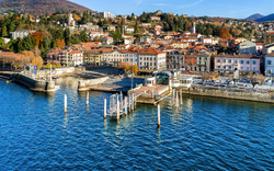 Kleinstadt am Seeufer mit Anlegestelle und Hügeln im Hintergrund.