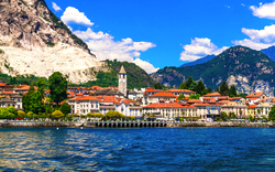 Blick auf die Promenade von Baveno am Lago Maggiore, umgeben von Bergen, an einem sonnigen Tag.