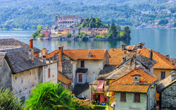 Blick auf Ortschaft mit bunten Dächern und See im Hintergrund