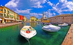 Bunte Häuser und Boote im Hafen einer historischen italienischen Stadt.