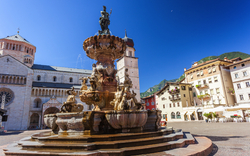 Brunnen auf einem historischen Platz mit Gebäuden im Hintergrund.