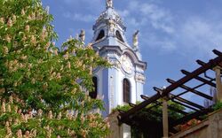Turm der Stiftskirche Dürnstein, umgeben von Blumen und blauem Himmel.