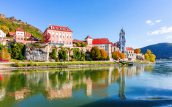 Historische Gebäude am Ufer eines Flusses bei sonnigem Wetter.