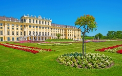 Barockes Schloss mit prächtigen Gärten und symmetrischen Blumenbeeten im Sommer.