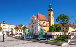 Platz mit gelbem Gebäude, Kirche, Brunnen und blauen Himmel