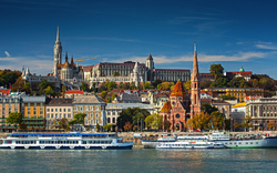 Panorama von Budapest mit Gebäuden und Fluss, bei blauem Himmel.