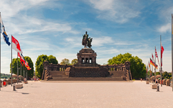 Reiterstandbild am Deutschen Eck in Koblenz mit Flaggen im Vordergrund.