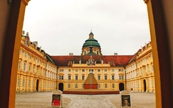 Barocker Innenhof mit prächtiger Kuppel, gelb-orangene Fassade und Pflastersteine.