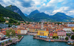 Küstenstadt mit bunten Gebäuden vor bewaldeten Bergen und blauem Himmel