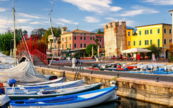 Boote im Altstadthafen von Bardolino am Gardasee mit bunten Gebäuden im Hintergrund.