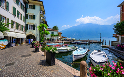 Boote im Hafen neben einem Kopfsteinpflasterweg, umgeben von bunten Gebäuden.