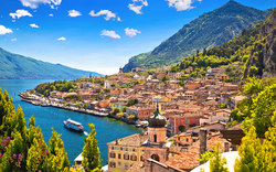 Küstenstadt am See mit Bergen im Hintergrund unter blauem Himmel.