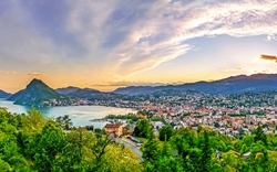 Panoramablick auf eine Stadt am See mit Bergen bei Sonnenuntergang.